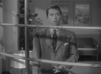 Movie still from “Now, Voyager” (1942), directed by Irving Rapper – A black and white photo of a man looking out a window; Medium shot, Over the shoulder angle
