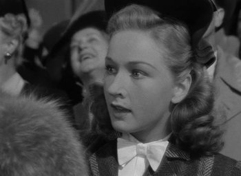 Movie still from “Now, Voyager” (1942), directed by Irving Rapper – A young woman in a bow tie and a fur coat; Close Up shot, Over the shoulder angle