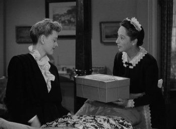 Movie still from “Now, Voyager” (1942), directed by Irving Rapper – Two women are talking to each other while holding a box; Medium shot, High angle