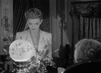 Movie still from “Now, Voyager” (1942), directed by Irving Rapper – An old photo of a woman sitting at a dinner table; Medium shot, Over the shoulder angle