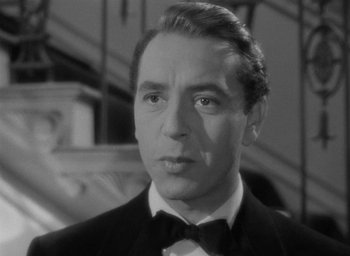 Movie still from “Now, Voyager” (1942), directed by Irving Rapper – A black and white photo of a man in a tuxedo; Close Up shot, Low angle