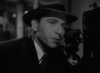 Movie still from “Now, Voyager” (1942), directed by Irving Rapper – A black and white photo of a man in a fedora; Close Up shot, High angle