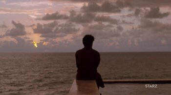 A man sitting on a ledge looking out at the ocean