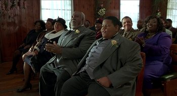 Movie still from “Nutty Professor II: The Klumps” (2000), directed by Peter Segal – A couple of men sitting next to each other on chairs; Medium shot, Low angle