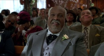 Movie still from “Nutty Professor II: The Klumps” (2000), directed by Peter Segal – An older man wearing a suit and tie with a flower in his lapel; Close Up shot, Low angle