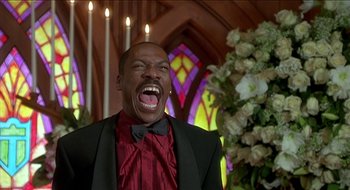 Movie still from “Nutty Professor II: The Klumps” (2000), directed by Peter Segal – A man in a suit and bow tie laughing; Close Up shot, Low angle