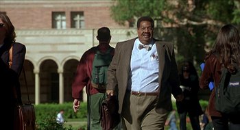 Movie still from “Nutty Professor II: The Klumps” (2000), directed by Peter Segal – A man walking down a sidewalk with a backpack; Medium shot, Low angle