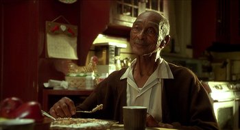 Movie still from “Nutty Professor II: The Klumps” (2000), directed by Peter Segal – An older man sitting at a table with a plate of food; Close Up shot, Over the shoulder angle