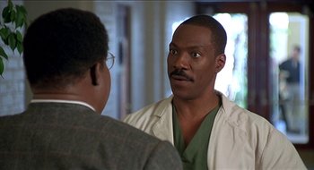 Movie still from “Nutty Professor II: The Klumps” (2000), directed by Peter Segal – A man in a white lab coat talking to another man in a suit; Close Up shot, Over the shoulder angle