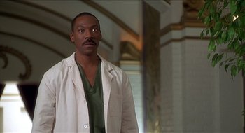 Movie still from “Nutty Professor II: The Klumps” (2000), directed by Peter Segal – A man wearing a lab coat standing next to a wall; Medium shot, Low angle