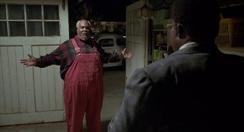 Movie still from “Nutty Professor II: The Klumps” (2000), directed by Peter Segal – A man in red overalls standing next to another man in a suit; Medium shot, Low angle