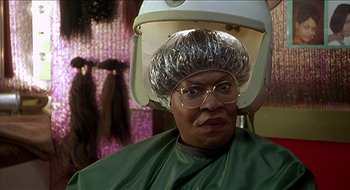Movie still from “Nutty Professor II: The Klumps” (2000), directed by Peter Segal – A woman sitting in a chair with a hair dryer on her head; Close Up shot, Over the shoulder angle