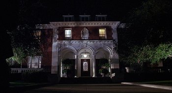 Movie still from “Nutty Professor II: The Klumps” (2000), directed by Peter Segal – A large building with a large window at night time; Wide shot, Low angle