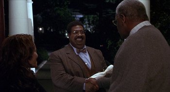 Movie still from “Nutty Professor II: The Klumps” (2000), directed by Peter Segal – A man in a suit shaking hands with another man; Medium shot, Over the shoulder angle