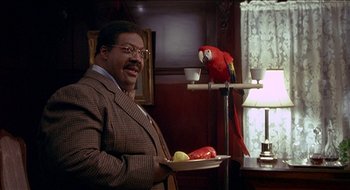 Movie still from “Nutty Professor II: The Klumps” (2000), directed by Peter Segal – A man holding a plate with a parrot on top of it; Medium shot, Low angle