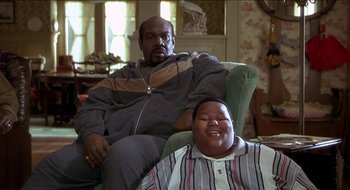 Movie still from “Nutty Professor II: The Klumps” (2000), directed by Peter Segal – A man sitting on a chair next to a boy; Medium shot, High angle