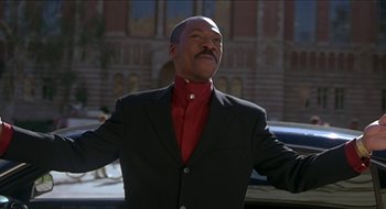 Movie still from “Nutty Professor II: The Klumps” (2000), directed by Peter Segal – A man in a black suit and a red tie; Medium shot, Low angle