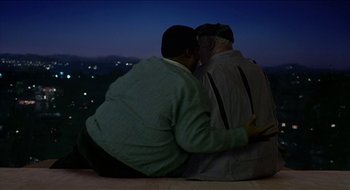 Movie still from “Nutty Professor II: The Klumps” (2000), directed by Peter Segal – Two men sitting on top of a building at night; Medium shot, High angle