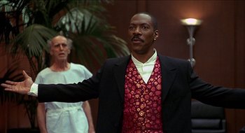 Movie still from “Nutty Professor II: The Klumps” (2000), directed by Peter Segal – A man in a suit and tie standing in front of another man in a suit and tie; Medium shot, Low angle