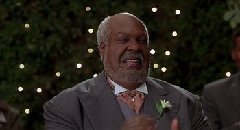 Movie still from “Nutty Professor II: The Klumps” (2000), directed by Peter Segal – An older man wearing a suit holding a white flower; Close Up shot, Low angle