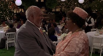 Movie still from “Nutty Professor II: The Klumps” (2000), directed by Peter Segal – An older man and a younger woman holding hands; Medium shot, High angle