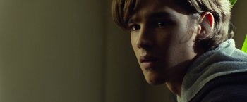 Movie still from “Oculus” (2013), directed by Mike Flanagan – A young man's face in the dark; Close Up shot, Over the shoulder angle