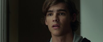 Movie still from “Oculus” (2013), directed by Mike Flanagan – A young man's face in a dark room; Close Up shot, Over the shoulder angle