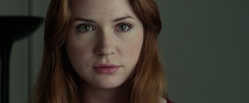 Movie still from “Oculus” (2013), directed by Mike Flanagan – A woman's face with green eyes; Close Up shot, Over the shoulder angle
