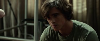 Movie still from “Oculus” (2013), directed by Mike Flanagan – A man with long hair and a green t - shirt looking to his left; Close Up shot, Over the shoulder angle