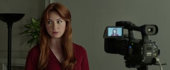 Movie still from “Oculus” (2013), directed by Mike Flanagan – A woman with long red hair is in front of a video camera; Close Up shot, Over the shoulder angle