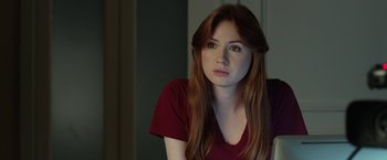 Movie still from “Oculus” (2013), directed by Mike Flanagan – A beautiful young lady with long red hair wearing a red shirt; Close Up shot, Over the shoulder angle