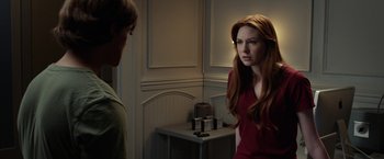 Movie still from “Oculus” (2013), directed by Mike Flanagan – A woman with long red hair is standing next to a man; Medium shot, Over the shoulder angle