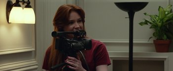 Movie still from “Oculus” (2013), directed by Mike Flanagan – A red haired woman holding a video camera up to her face; Close Up shot, Over the shoulder angle