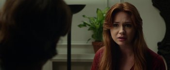 Movie still from “Oculus” (2013), directed by Mike Flanagan – A woman with long red hair sitting in front of a potted plant; Close Up shot, Over the shoulder angle