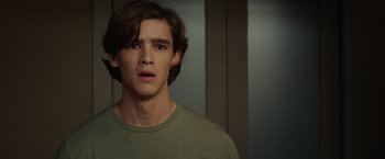 Movie still from “Oculus” (2013), directed by Mike Flanagan – A young man in a green shirt looking at the camera; Close Up shot, Over the shoulder angle