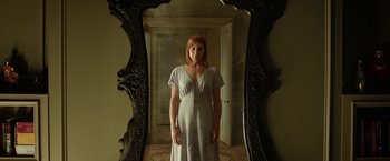 Movie still from “Oculus” (2013), directed by Mike Flanagan – A woman standing in front of a mirror in front of a door; Medium shot, Low angle
