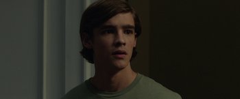 Movie still from “Oculus” (2013), directed by Mike Flanagan – A young man with long hair and a green shirt; Close Up shot, Over the shoulder angle