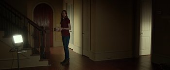 Movie still from “Oculus” (2013), directed by Mike Flanagan – A woman standing in a dark room holding a box; Wide shot, Low angle