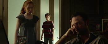 Movie still from “Oculus” (2013), directed by Mike Flanagan – A man and a woman standing next to a young boy; Medium shot, Over the shoulder angle