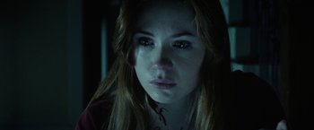 Movie still from “Oculus” (2013), directed by Mike Flanagan – A young woman is crying in a dark room; Close Up shot, Over the shoulder angle