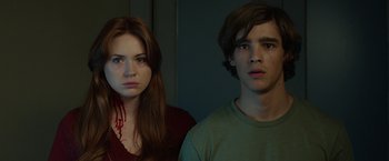 Movie still from “Oculus” (2013), directed by Mike Flanagan – A young man and a young woman standing next to each other; Medium shot, Low angle