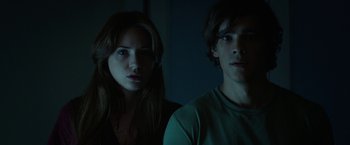 Movie still from “Oculus” (2013), directed by Mike Flanagan – A man and a woman standing next to each other in the dark; Medium shot, Low angle