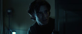 Movie still from “Oculus” (2013), directed by Mike Flanagan – A young man with long dark hair looking at the camera; Close Up shot, Low angle