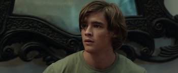 Movie still from “Oculus” (2013), directed by Mike Flanagan – A man with long hair and a green t - shirt looking to his left; Close Up shot, Over the shoulder angle