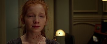 Movie still from “Oculus” (2013), directed by Mike Flanagan – A young girl with red hair and some blood on her face; Close Up shot, High angle