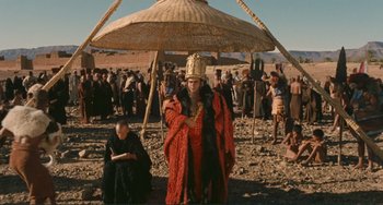 Movie still from “Oedipus Rex” (1967), directed by Pier Paolo Pasolini – A man dressed as a king standing under an umbrella in the desert; Wide shot, Low angle