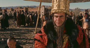 Movie still from “Oedipus Rex” (1967), directed by Pier Paolo Pasolini – A man wearing a gold hat and a red robe; Close Up shot, Over the shoulder angle