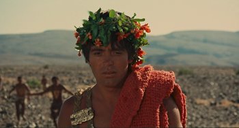 Movie still from “Oedipus Rex” (1967), directed by Pier Paolo Pasolini – A man wearing a wreath of flowers on his head; Close Up shot, Over the shoulder angle
