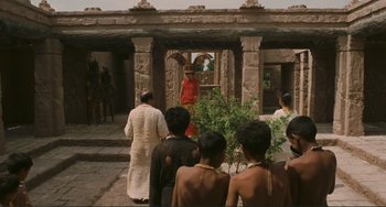 Movie still from “Oedipus Rex” (1967), directed by Pier Paolo Pasolini – A group of people standing in front of a stone building; Extreme Wide shot, Over the shoulder angle