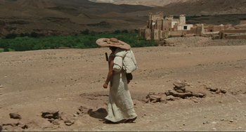 Movie still from “Oedipus Rex” (1967), directed by Pier Paolo Pasolini – A woman in a white dress and a straw hat walking in the desert; Extreme Wide shot, High angle